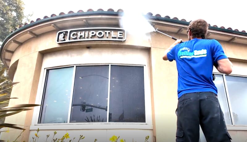 Rolling Suds technician pressure washing a restaurant storefront