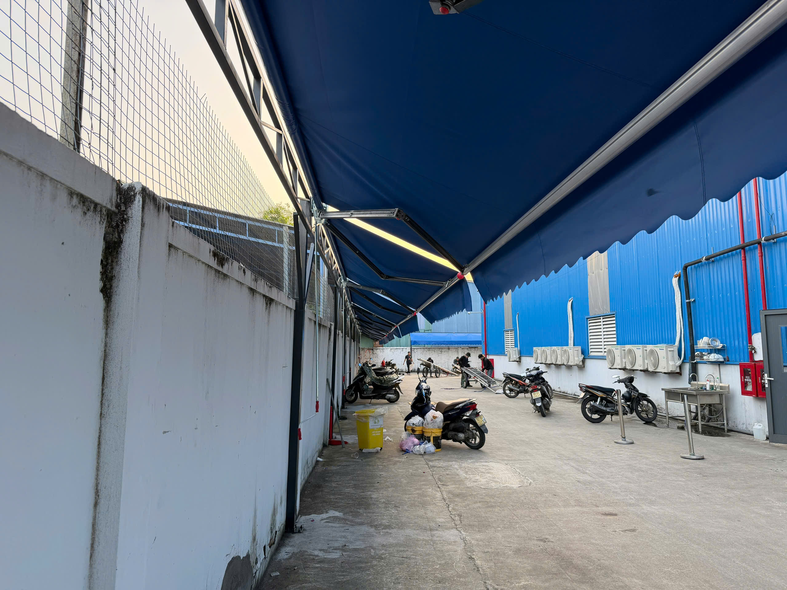 Dãy mái hiên di động màu xanh che nhà xe KCN Hòa Khánh