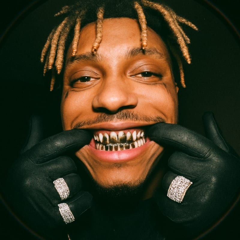 Juice Wrld. he haves face tattoos, tear tatoo. he is smiling at the camera with