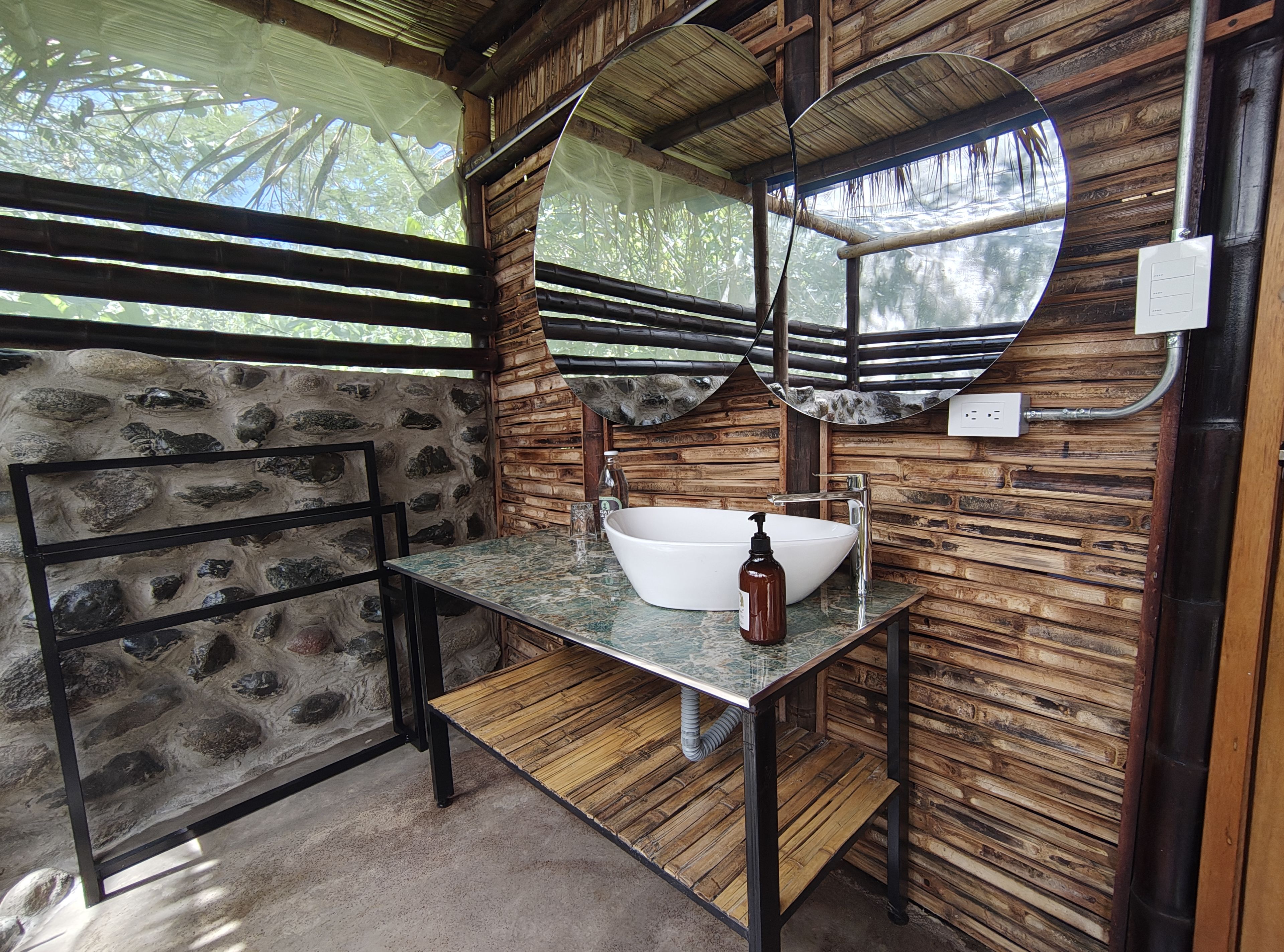 Área de lavamanos en baño al aire libre con bambú y acabados naturales