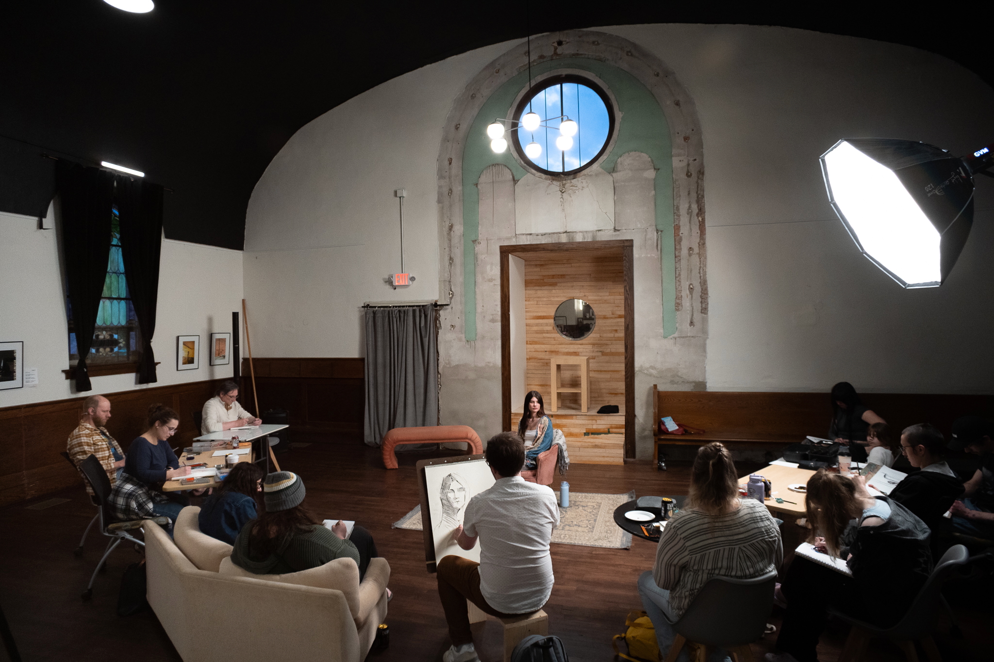 A group of artists drawing portraits of a model.