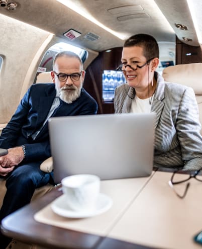 Two business executives working on a laptop in a private jet cabin