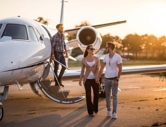 Passengers walking away from a private jet in golden evening light