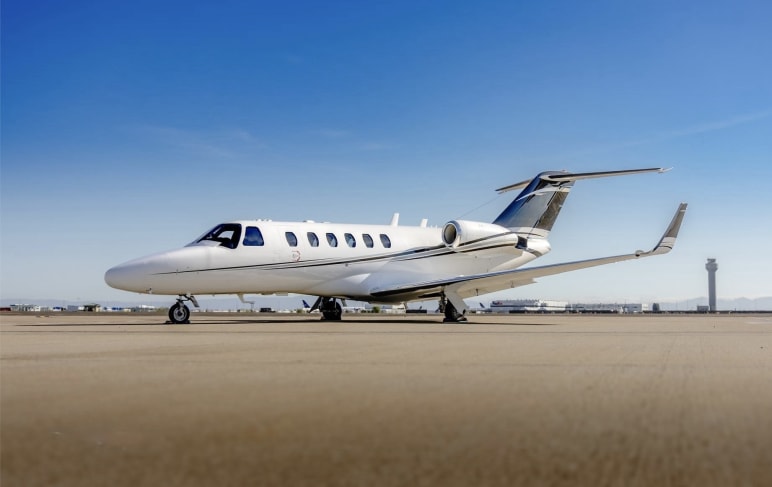 A private jet parked on a tarmac with an air traffic control tower in the background