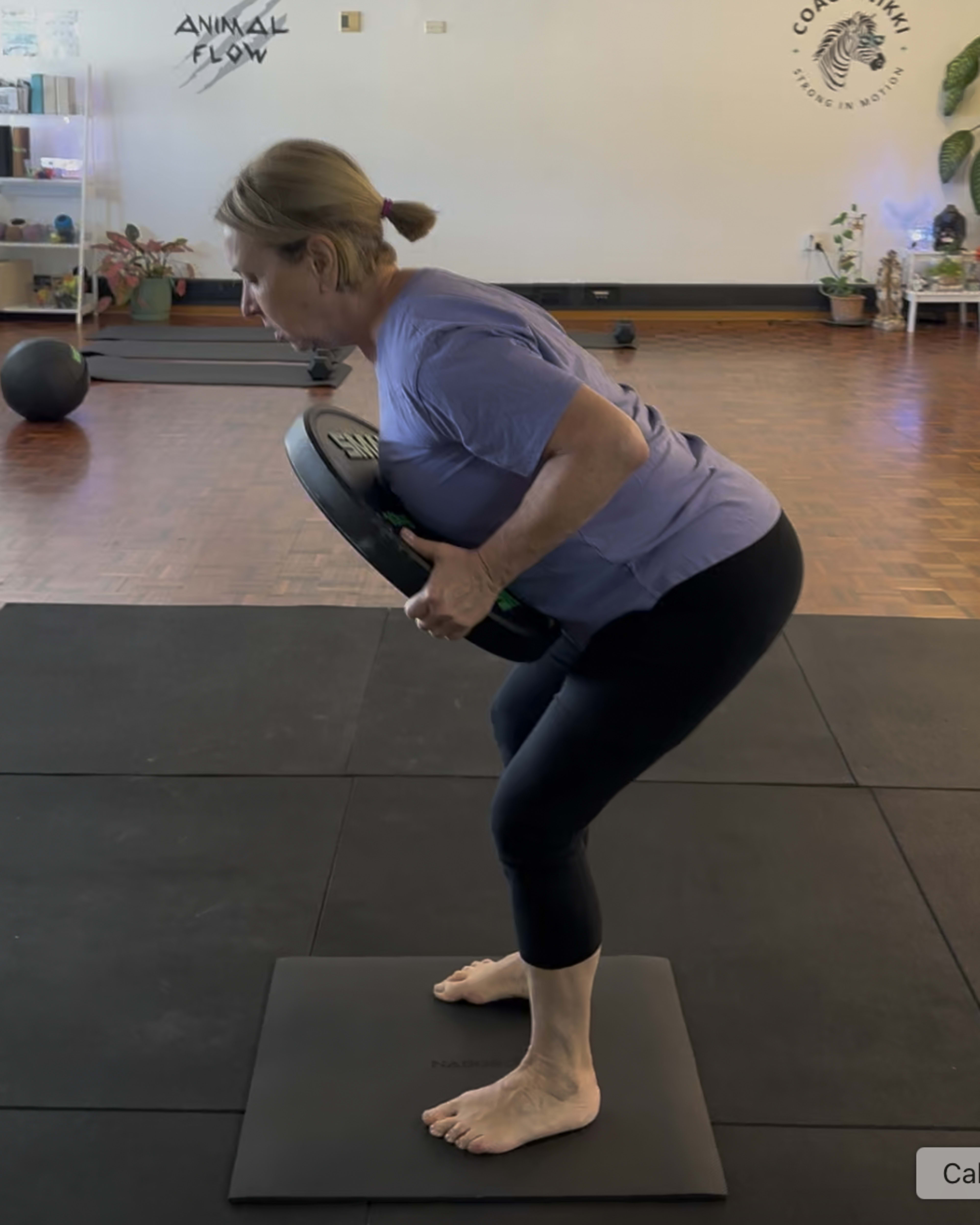 Senior client mid-deadlift, smiling