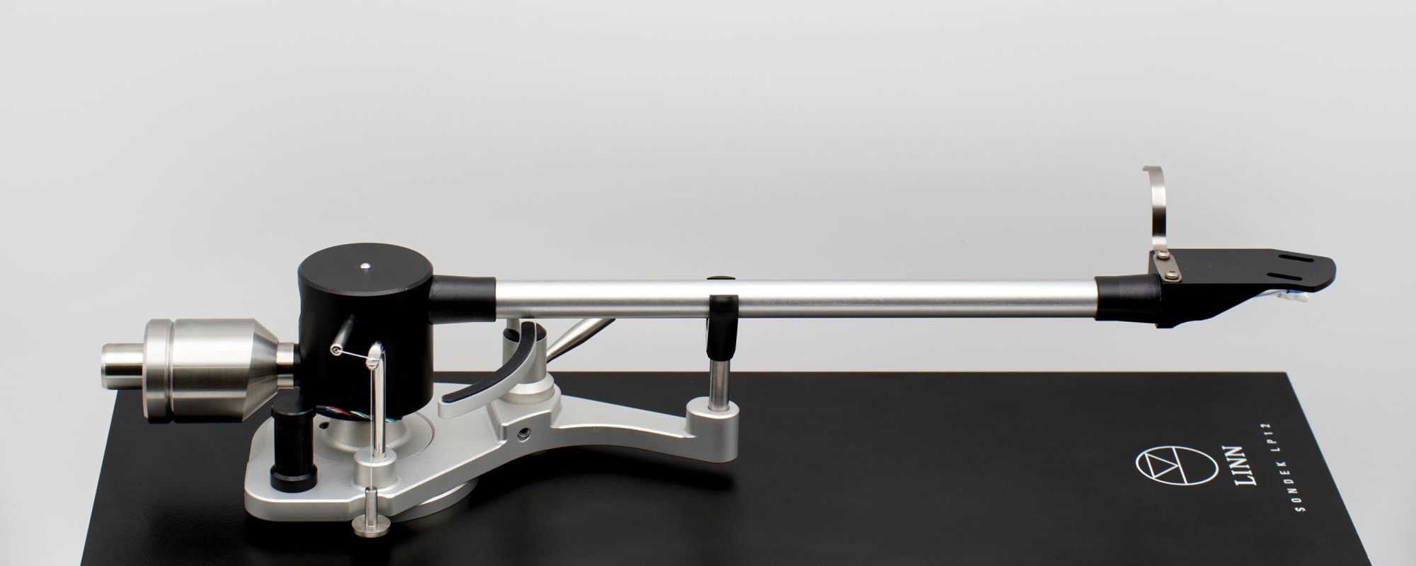 The Clear Wave tonearm seen side on against a plain backdrop, mounted on a Linn Sondek LP12 armboard, the arm tube running from the bearing housing out to the headshell