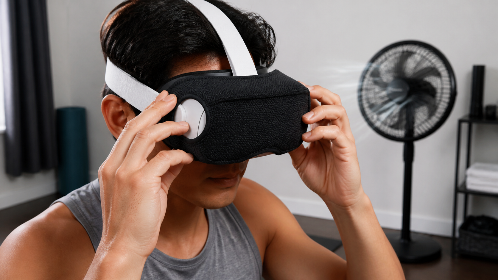 A person carefully fitting a VR sweat mask over their eyes with a room fan blowing in the background.