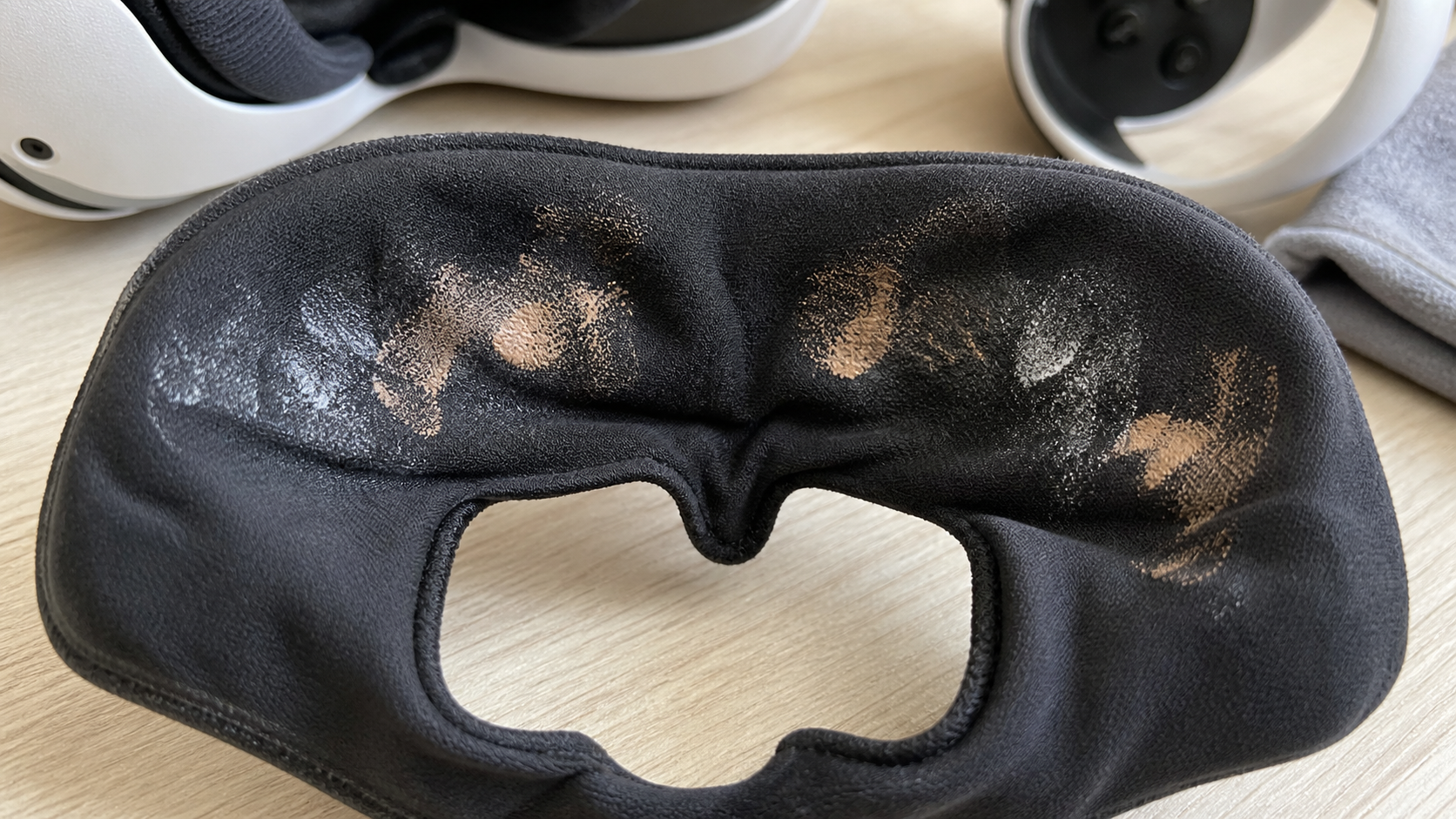 A VR sweat mask is shown with visible makeup and sunscreen residue after a gaming session in a hot room.