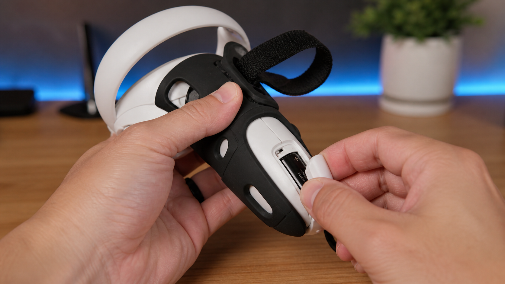 A person's hands struggling to open the battery compartment on a VR controller wrapped in a grip accessory