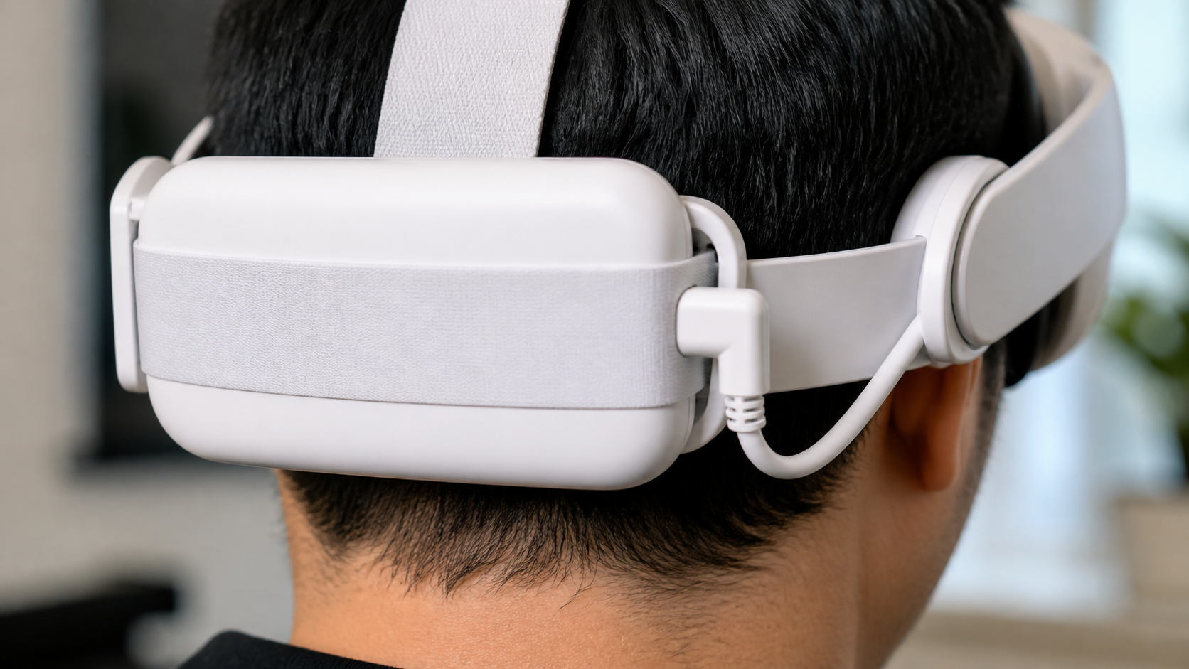 A close-up view of the back of a VR headset showing the short, stiff cable of a battery pack.