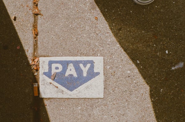A pay station sign painted on the sidewalk.