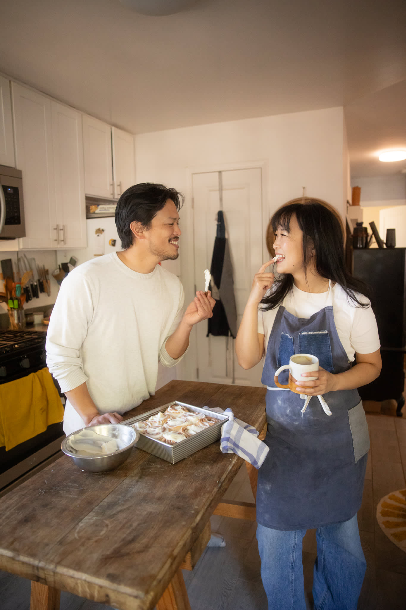 A couple enjoying a Cinnamon Roll in the kitchen