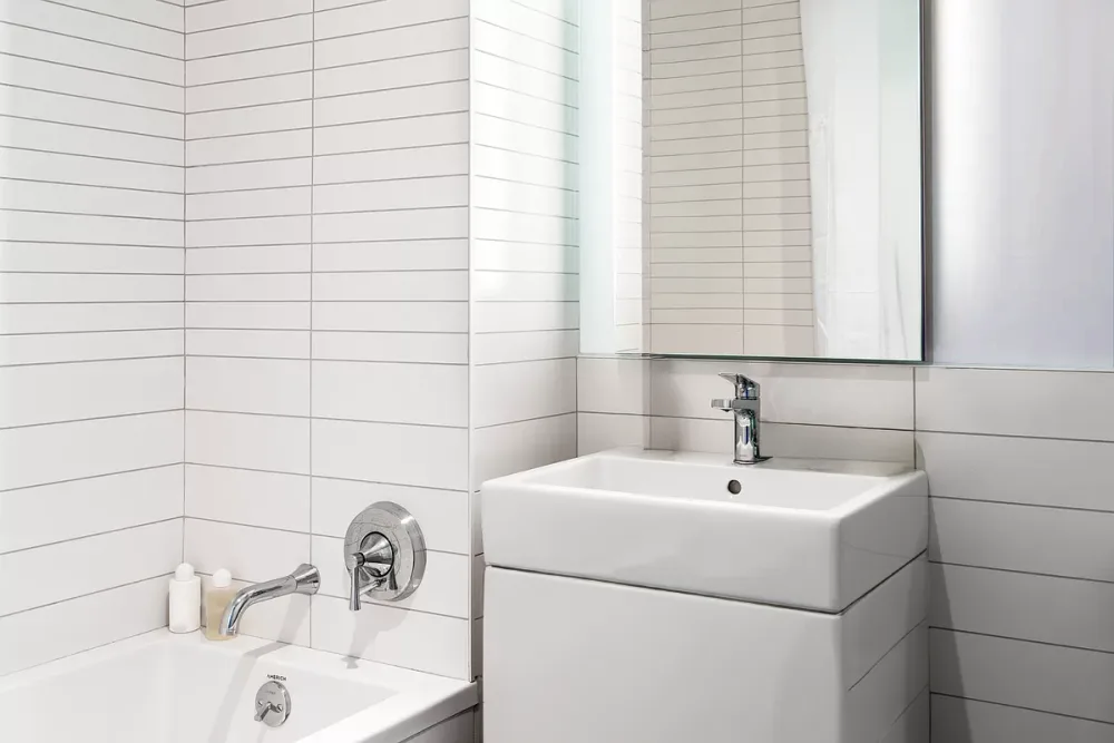 Modern, minimalist, white tiled bathroom.