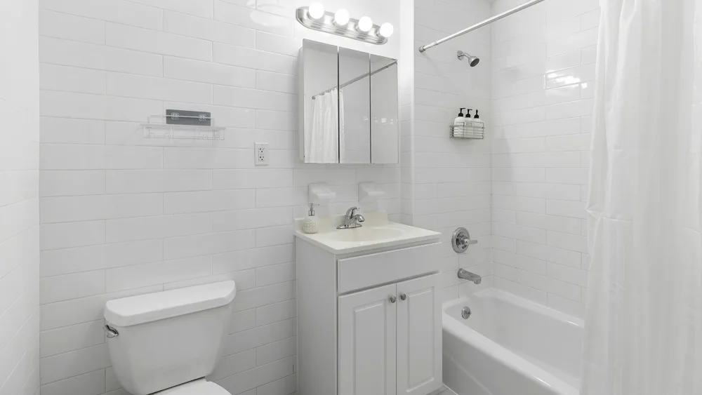 Modern, white-tiled bathroom with bathtub.