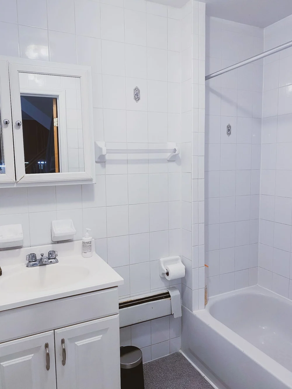 Bright white tiled bathroom with bathtub.