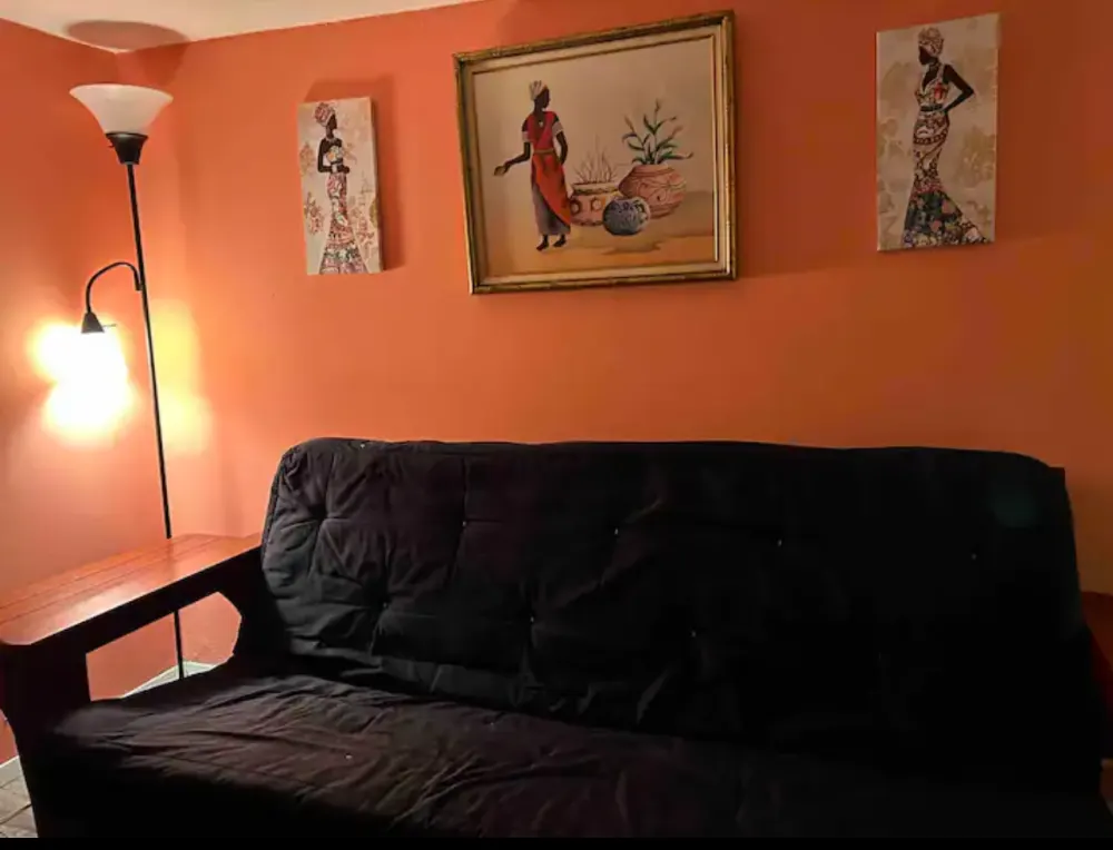 Orange wall, black couch, artistic decor.
