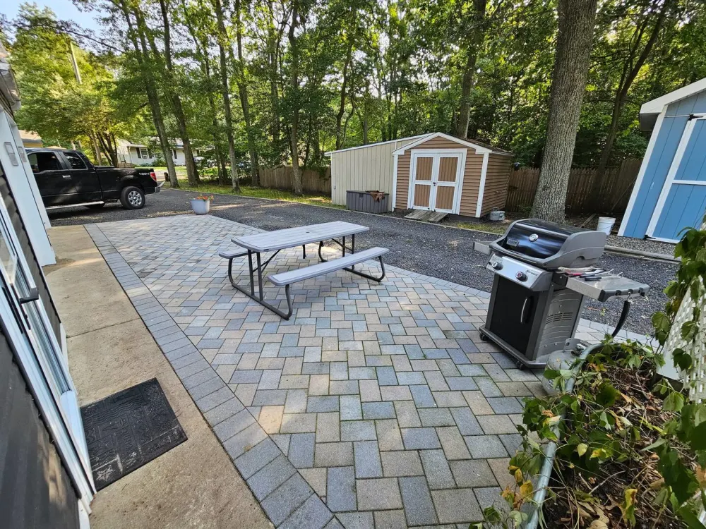 Paved patio with grill and picnic table.