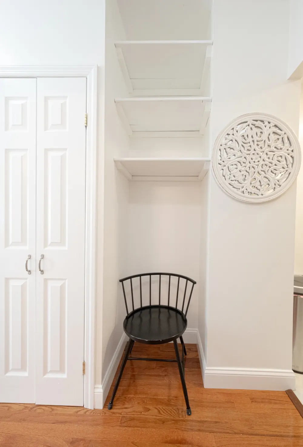 White closet, shelves, black chair, decor.