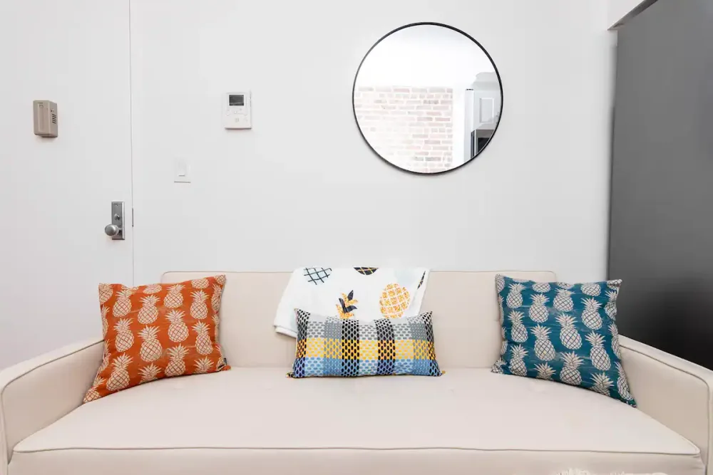 Stylish beige couch with pillows.