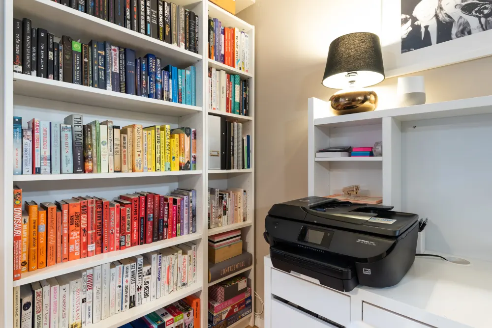 Colorful bookshelf and office printer.