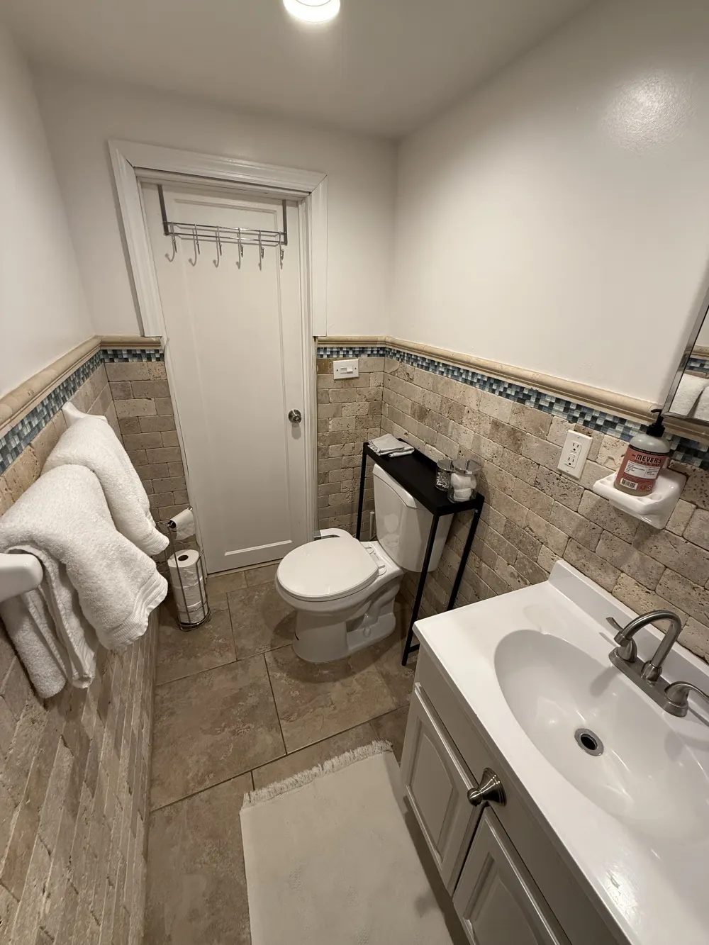 Compact bathroom with beige tiles.