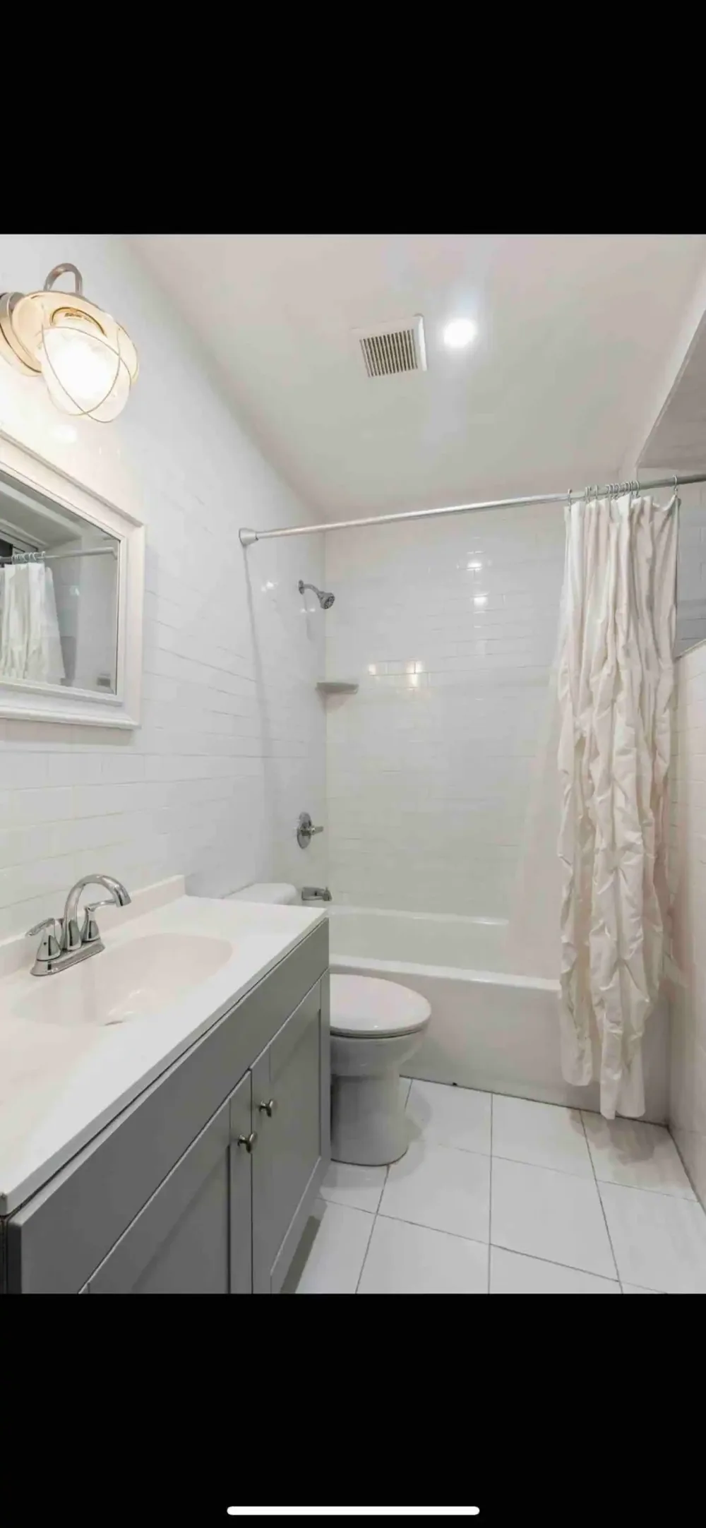 Modern, white-tiled bathroom with shower.