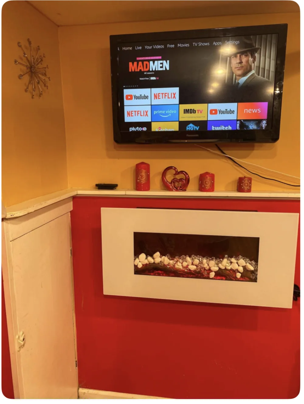 Wall-mounted TV above decorative fireplace.