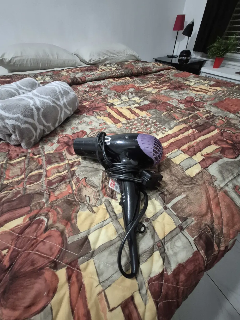 Hair dryer on patterned bedspread.
