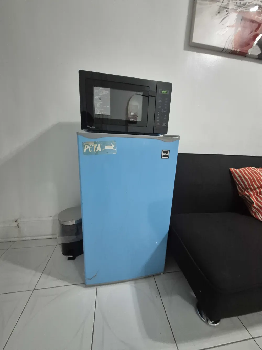 Microwave on blue mini fridge.