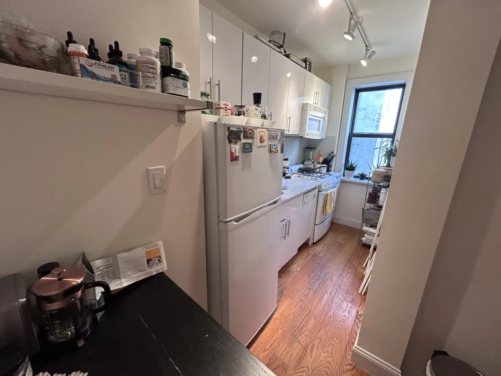 Narrow kitchen with white cabinets.