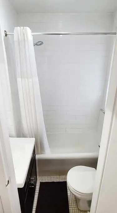 Compact, clean white-tiled bathroom.