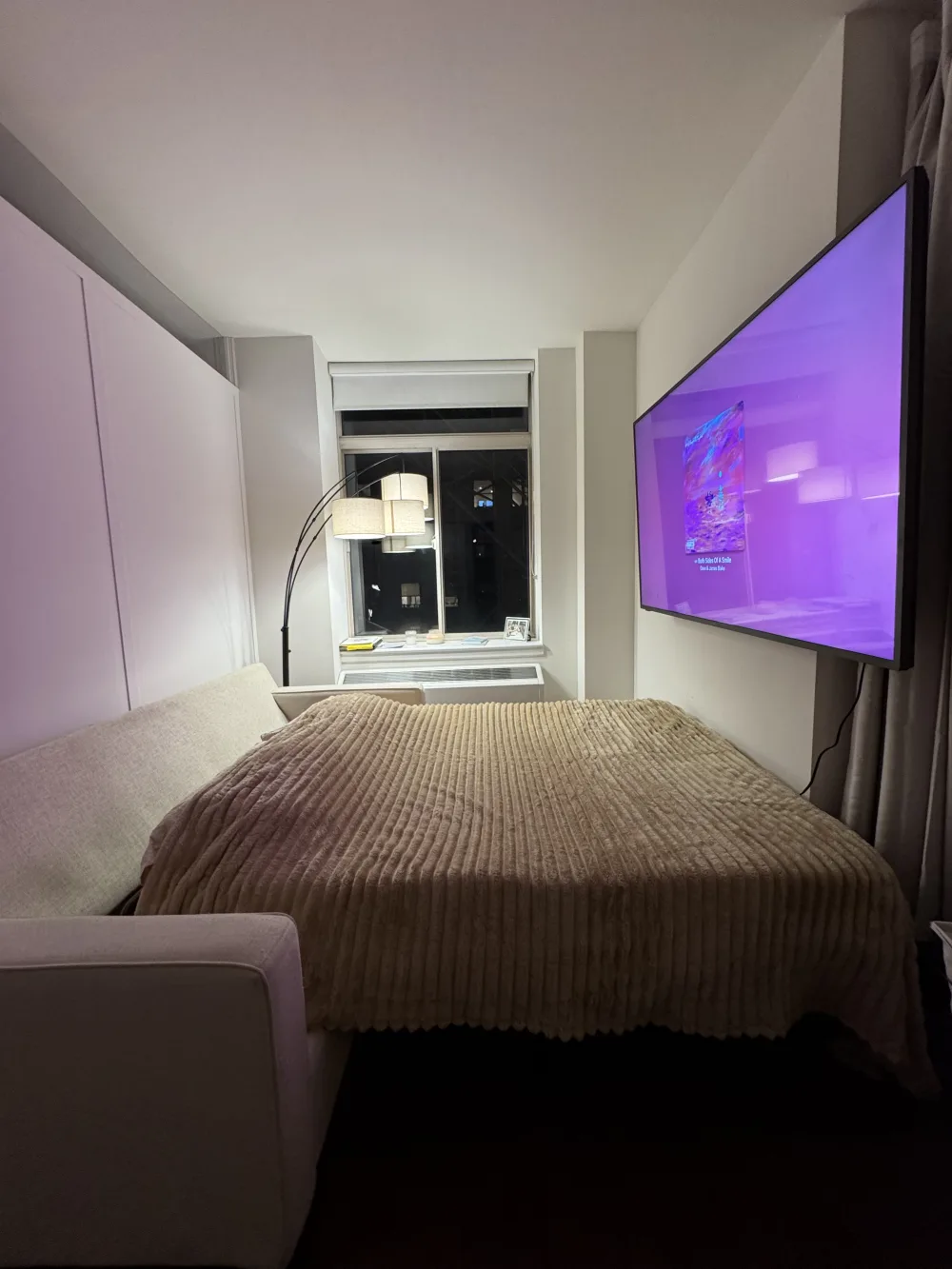 Cozy bedroom with TV and window.