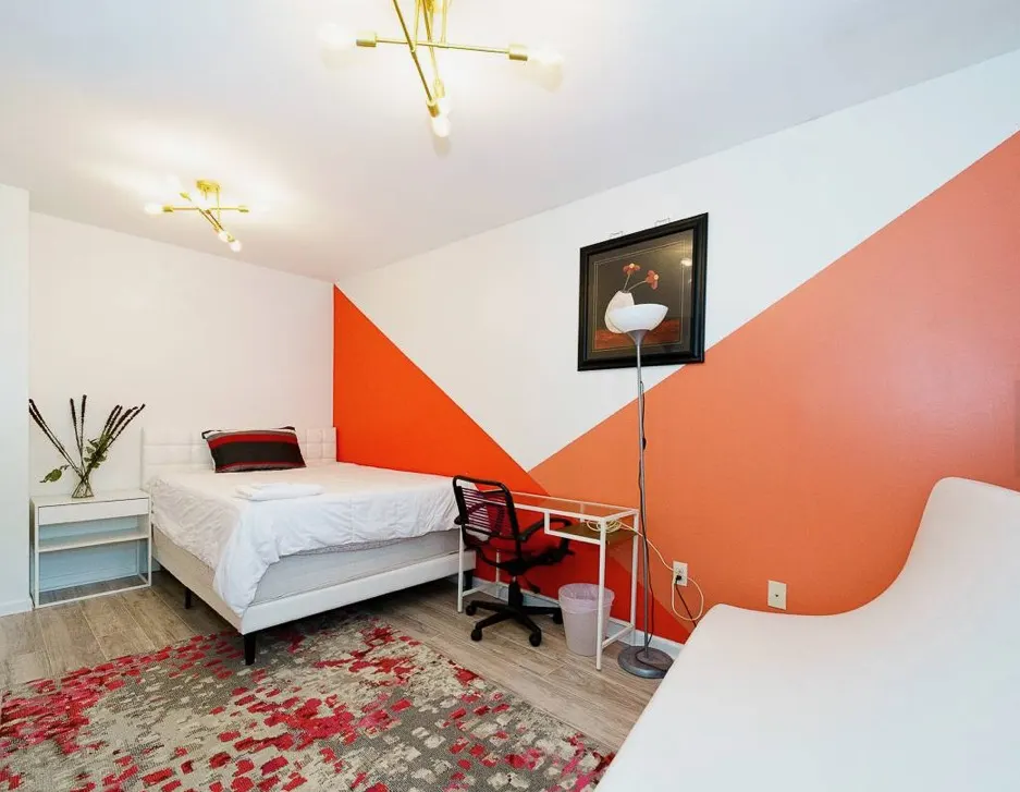 Modern bedroom with orange accent wall.