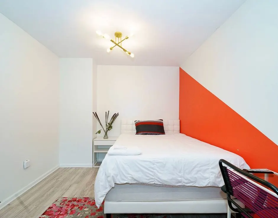 Modern minimal bedroom with orange accent.