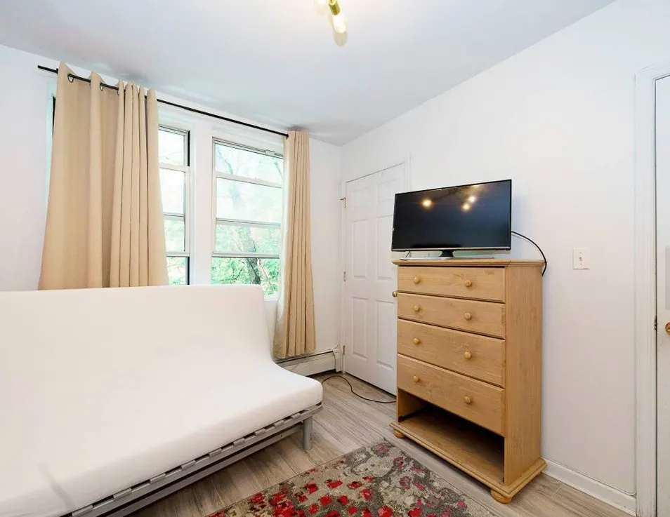 Bright room with futon, dresser.