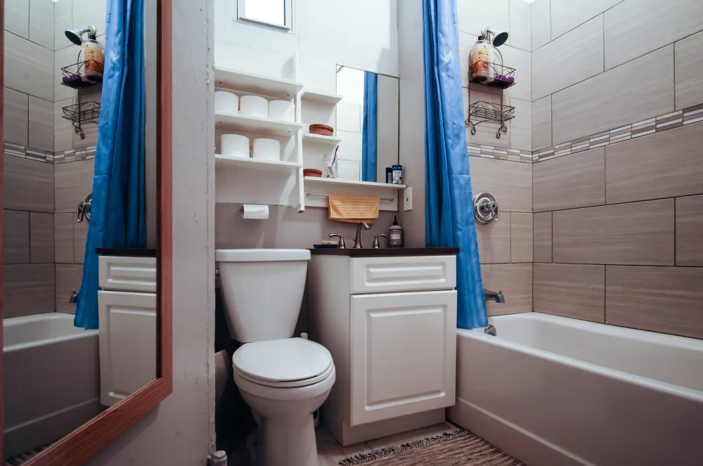 Compact bathroom with blue curtain.