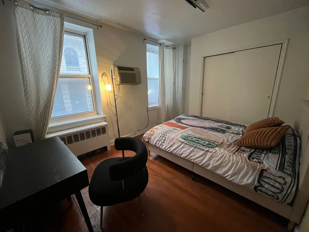 Cozy, sunlit bedroom with desk.
