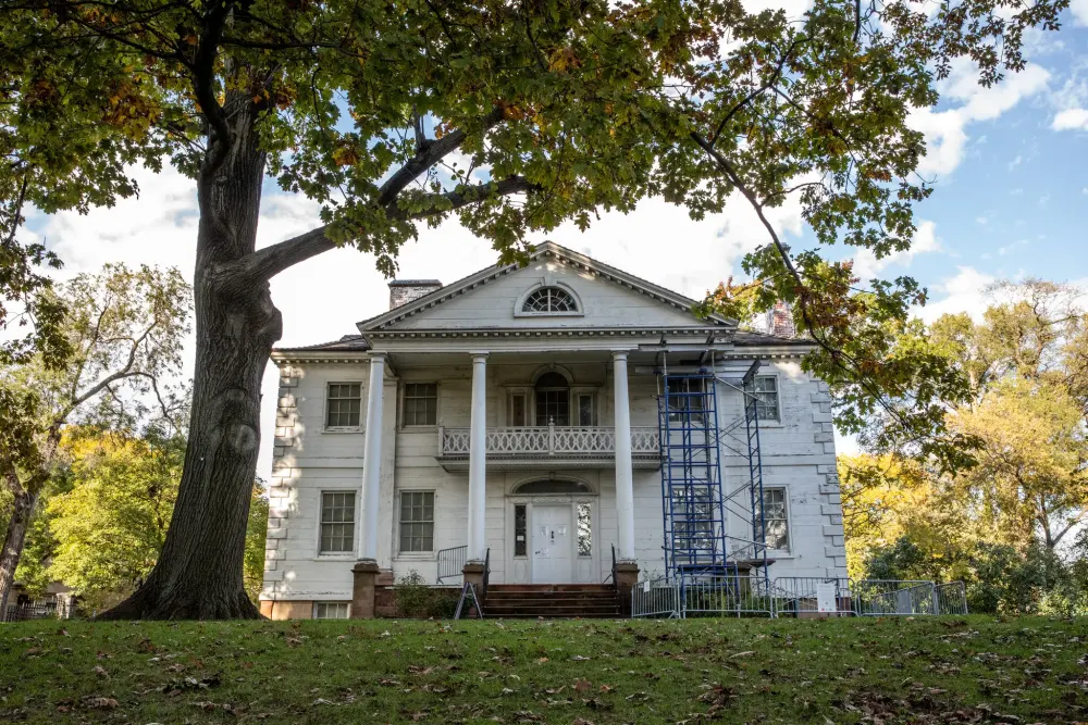 Woman in teal suit, bookshelves.