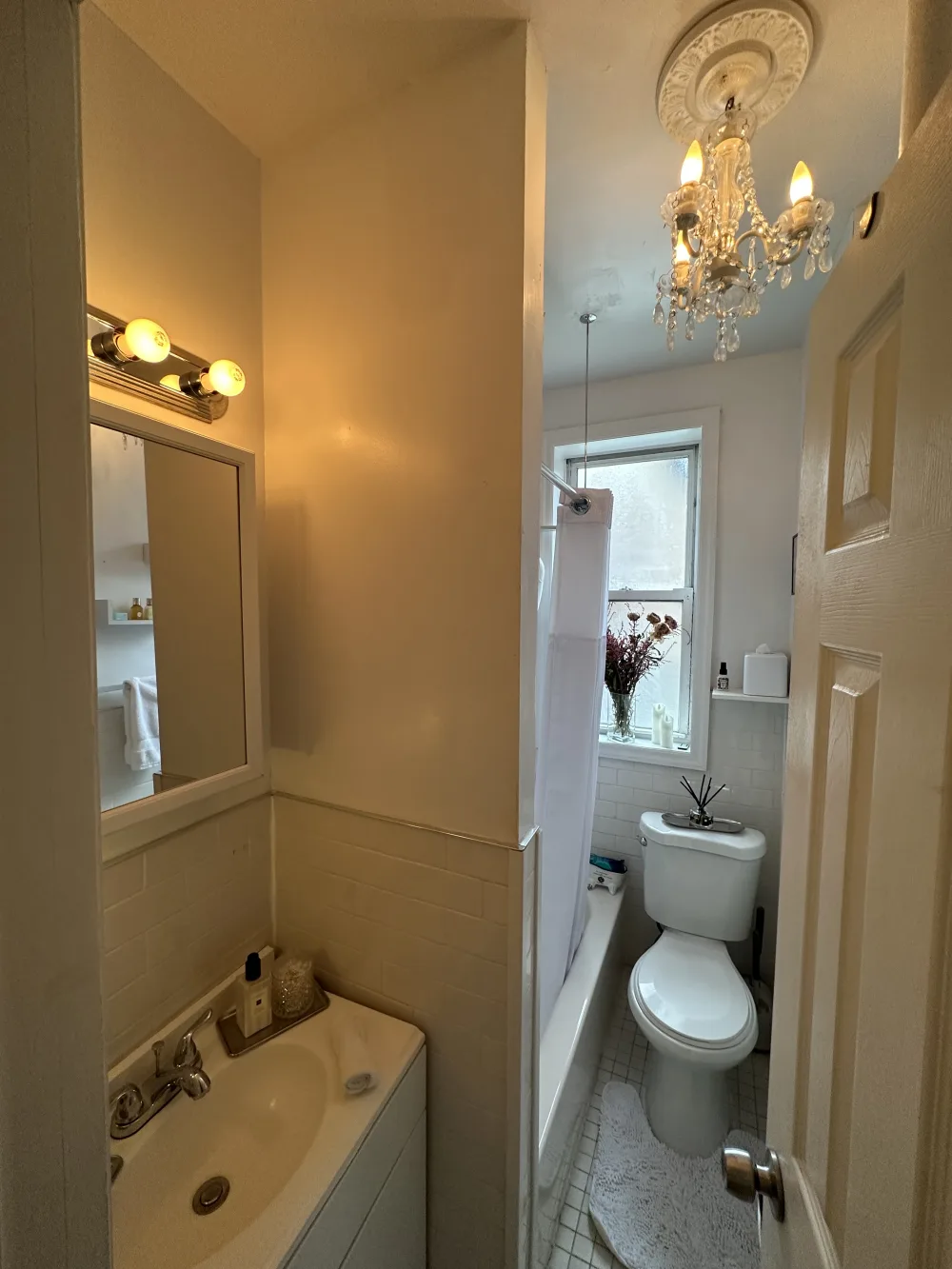 Small, cozy bathroom with chandelier.