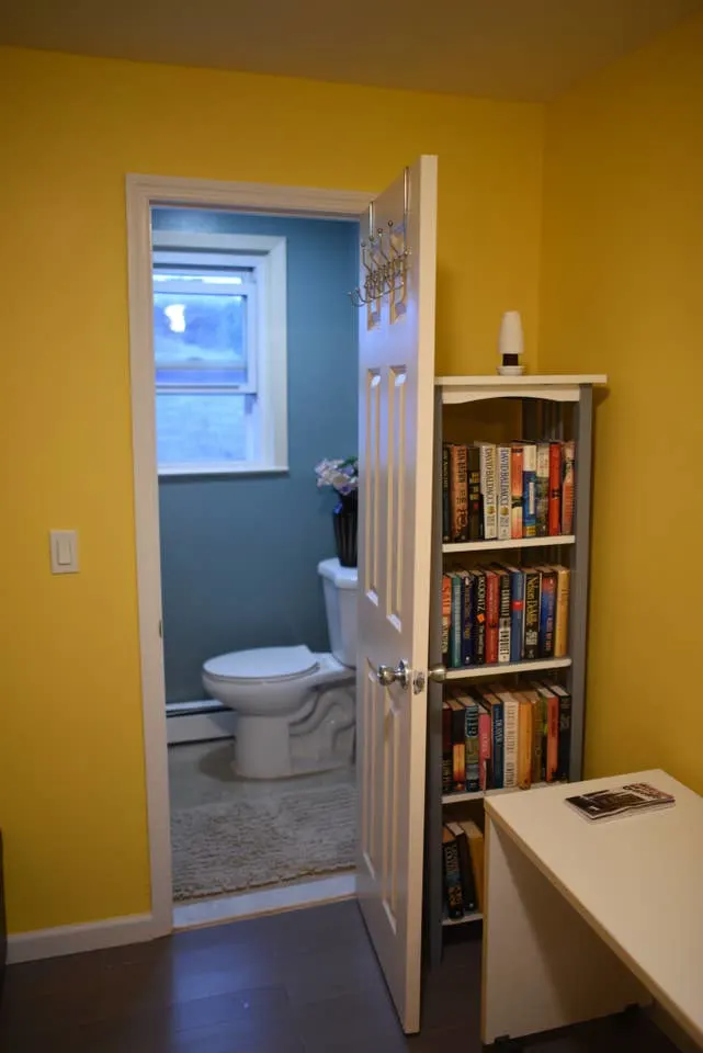 Bookshelf behind door, toilet visible.
