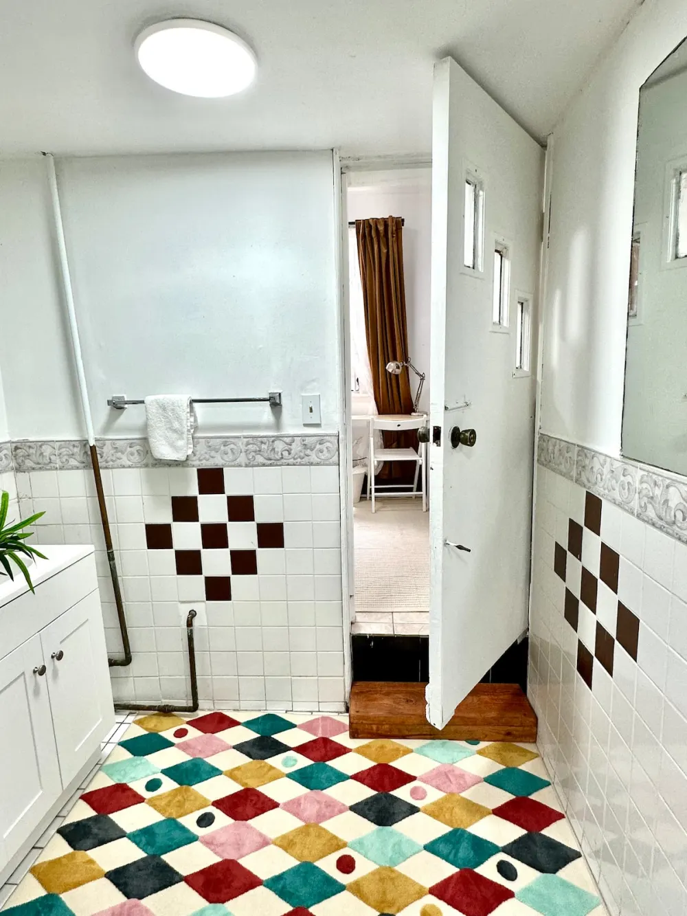 Colorful rug in tiled bathroom.