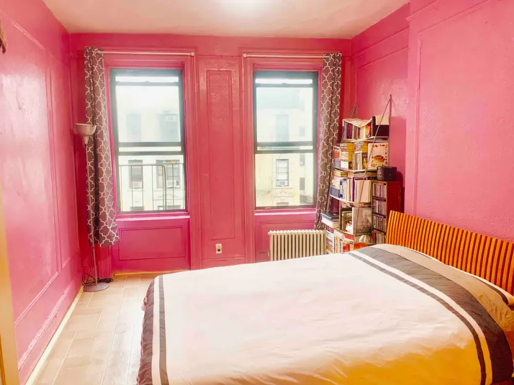 Bright pink-walled bedroom with books.