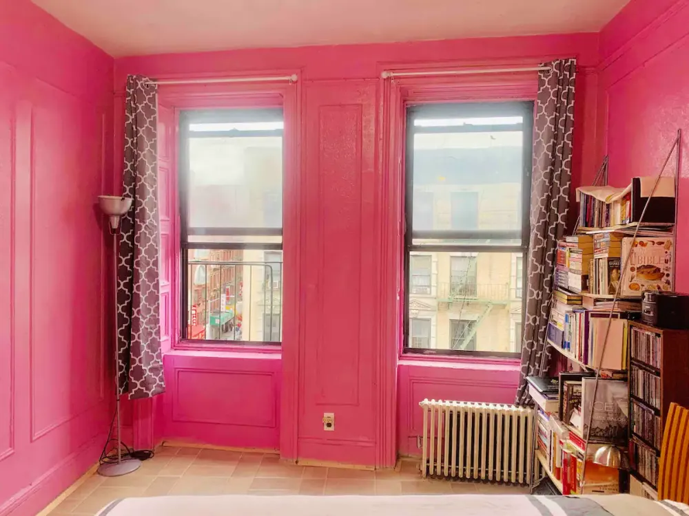 Bright pink-walled room, city view.