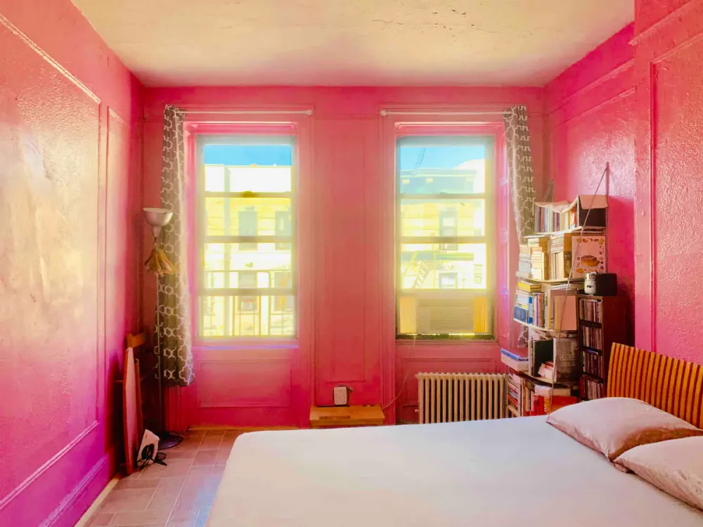 Bright pink bedroom with bookshelves.