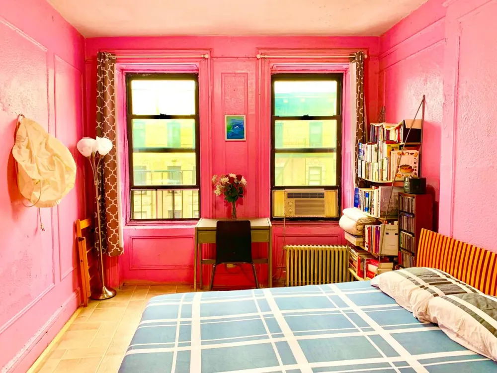Bright pink-walled bedroom with bookshelf.