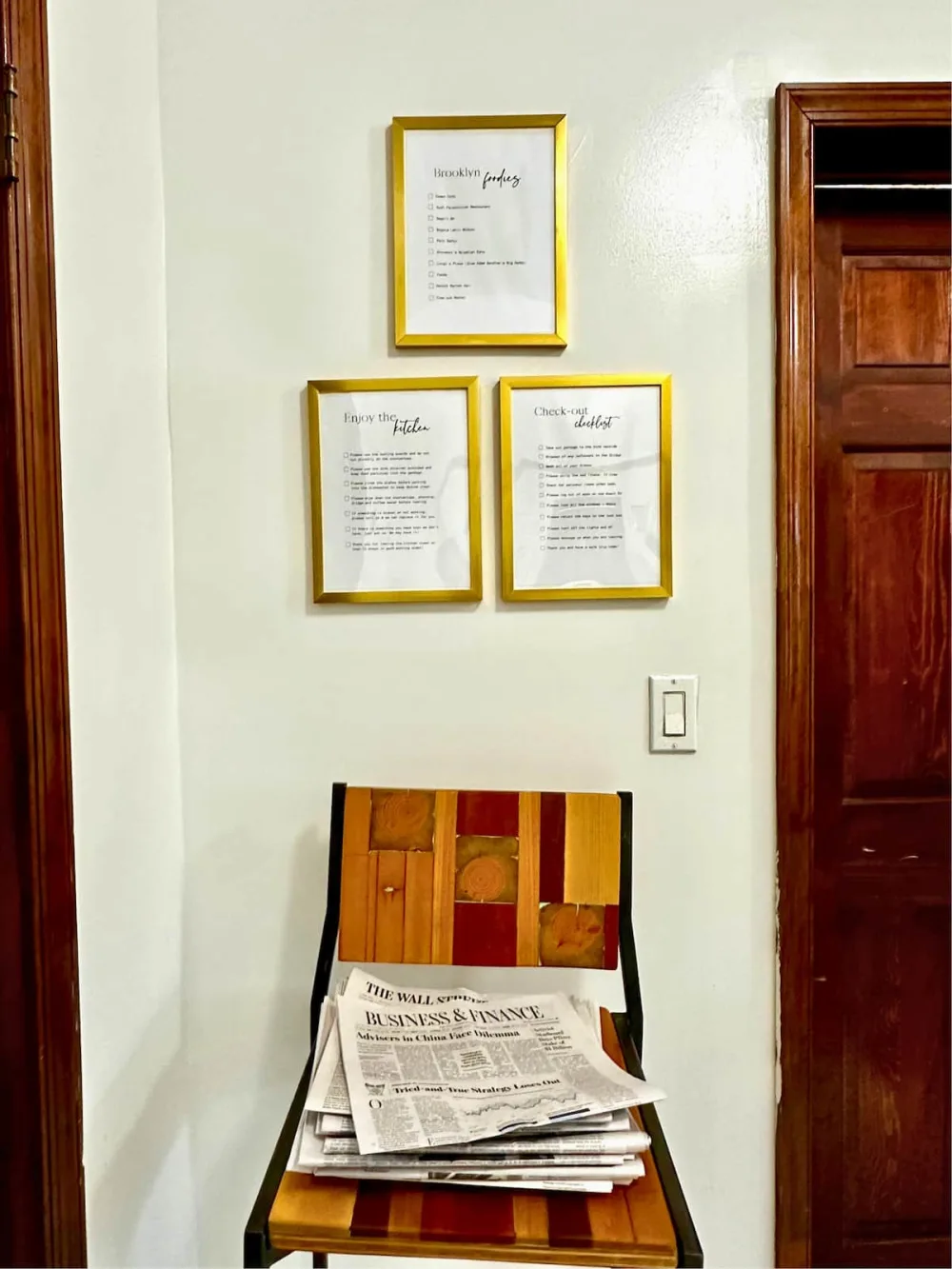 Framed lists above wooden chair.