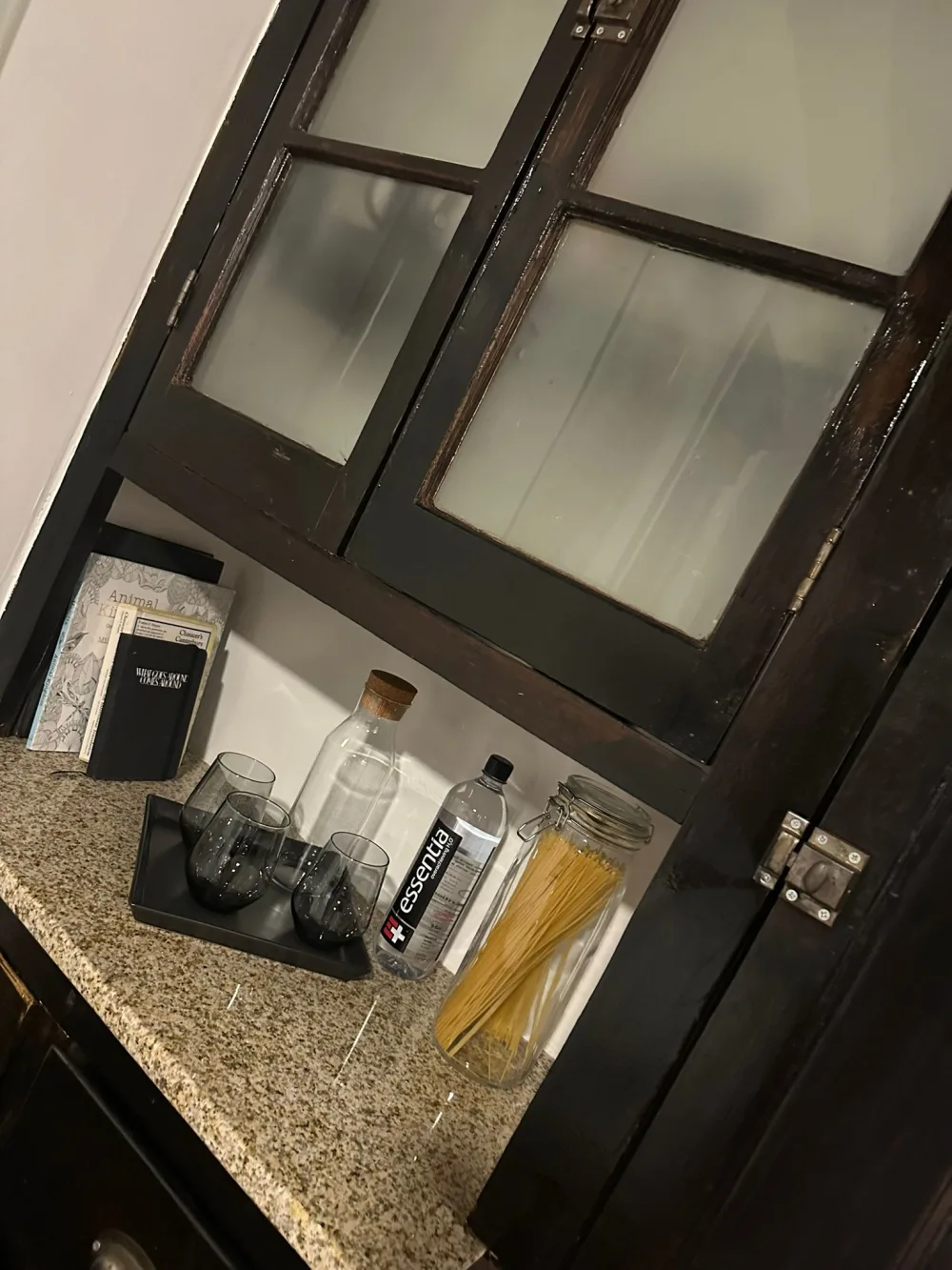 Dark cabinet, granite countertop, kitchen items.