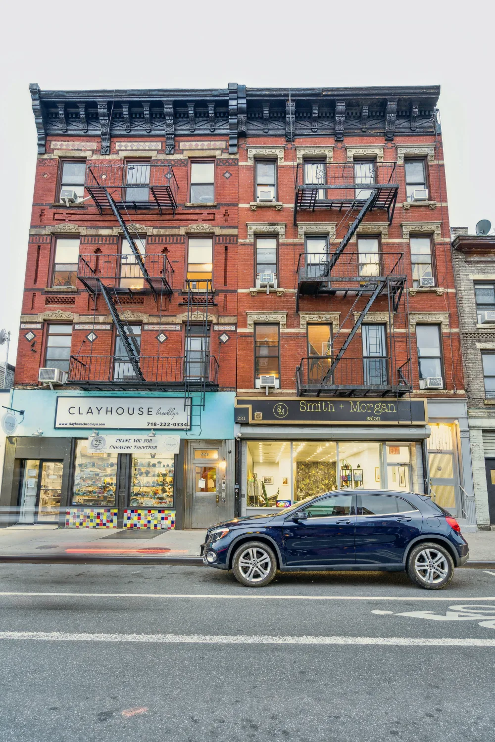 Brick building with storefronts, car.