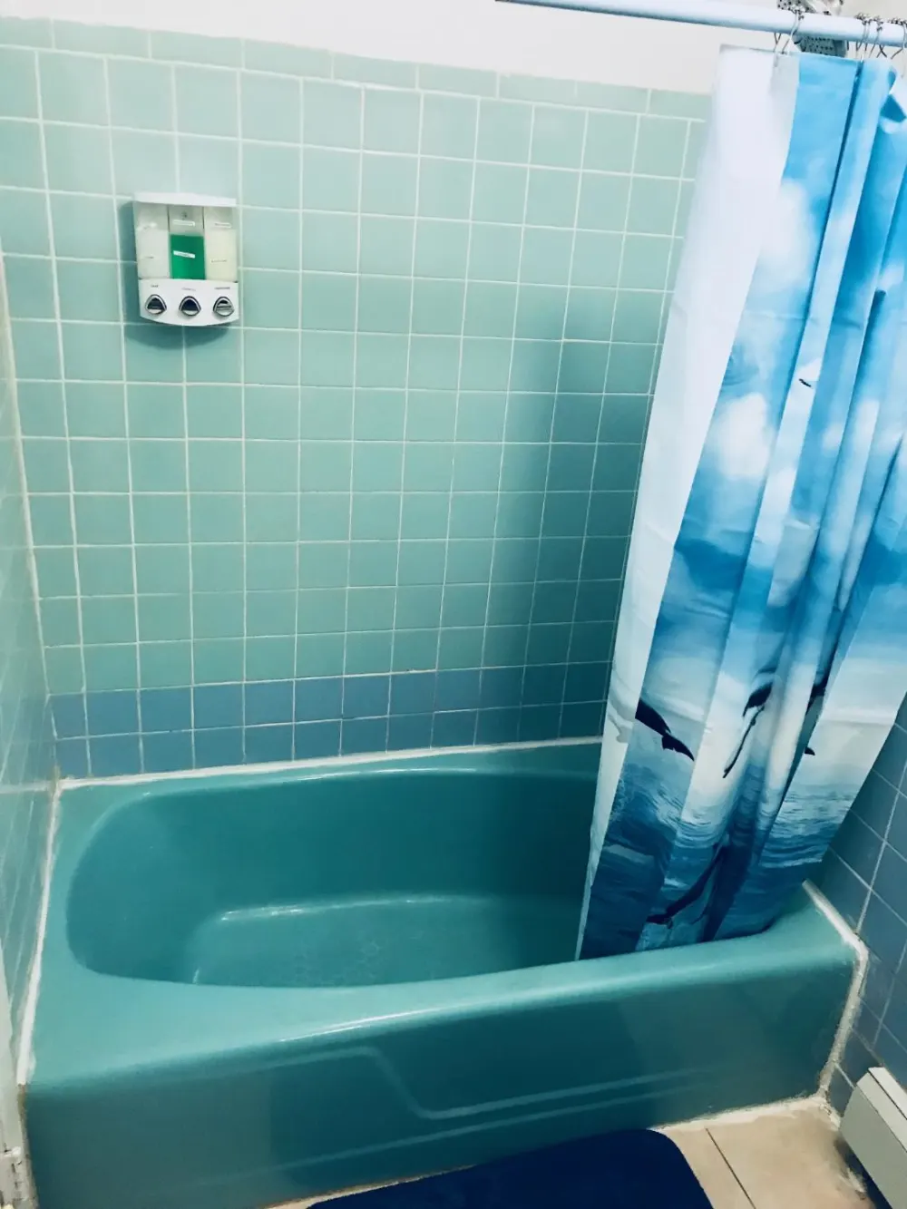 Turquoise bathtub with dolphin curtain.