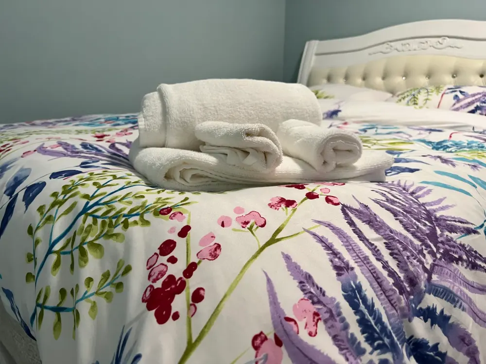 Floral bedspread with white towels.